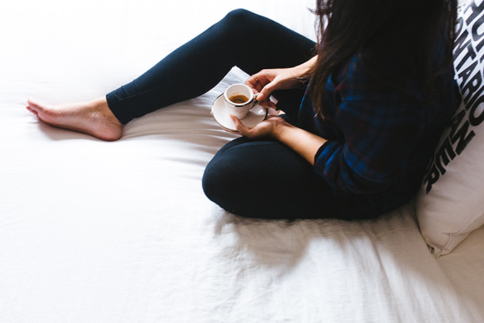 Girl holding a cup of coffee in bed