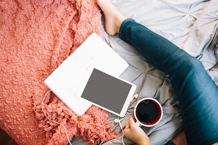 Girl on her bed with a tablet and drink