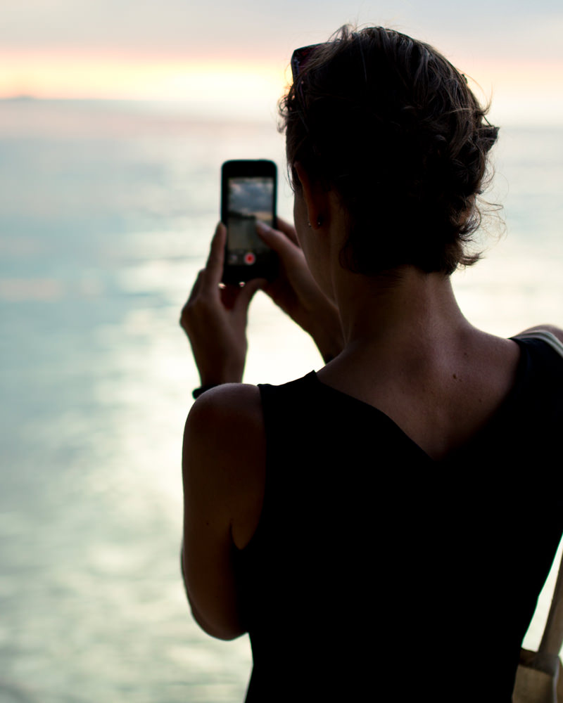 Girl taking a photo of the ocean